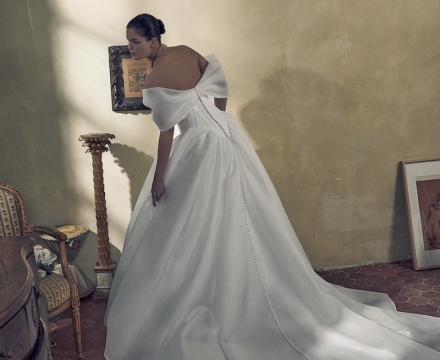 Abito da sposa principesco in mikado con scollatura omerale, fila di bottoncini e ampio strascico, presso Il Giardino Fiorito delle Spose a Roma.