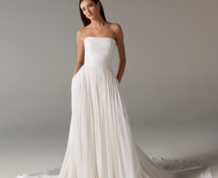 Abito da sposa minimal senza spalline, con gonna fluida e ampio strascico, presso Il Giardino Fiorito delle Spose a Roma.