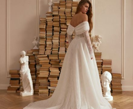 Abito da sposa principesco in pizzo con scollatura omerale, maniche lunghe e ampio strascico, presso Il Giardino Fiorito delle Spose a Roma.
