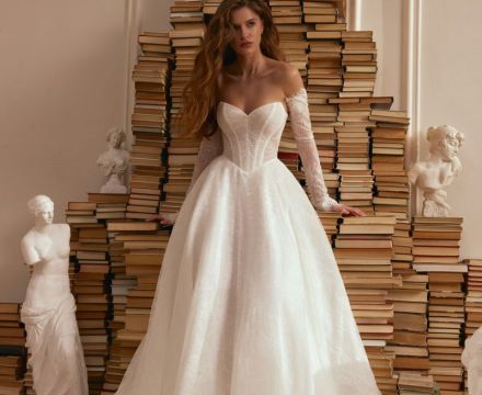 Abito da sposa principesco in pizzo con scollatura omerale, maniche lunghe e ampio strascico, presso Il Giardino Fiorito delle Spose a Roma.