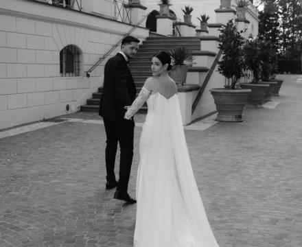 Sposa con abito couture e lungo strascico che cammina con lo sposo a Villa Miani Roma