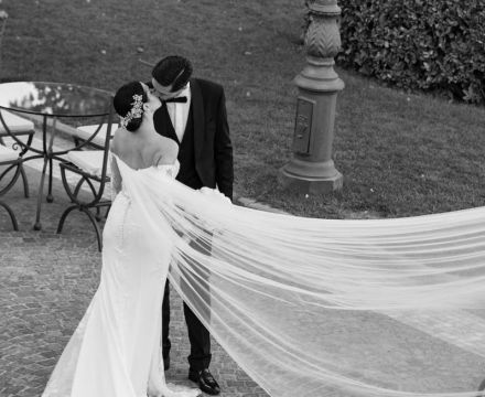 Sposa con abito couture e velo lungo che si bacia con lo sposo a Villa Miani Roma