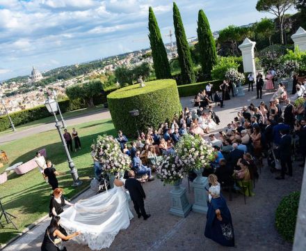 Cerimonia all’aperto a Villa Fonte Nuova con sposa e padre tra composizioni floreali e ospiti nel verde di Roma