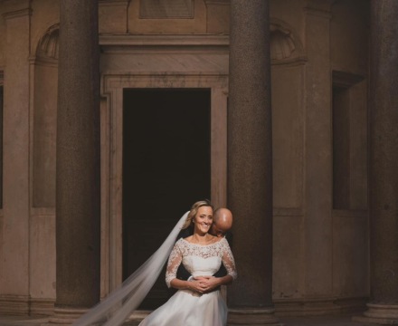 Sposa Il Giardino Fiorito delle Spose in abito con velo lungo in un momento intimo con lo sposo davanti a un’architettura classica