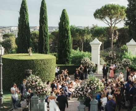 Cerimonia all’aperto a Villa Miani con sposa e padre tra composizioni floreali e ospiti nel verde di Roma