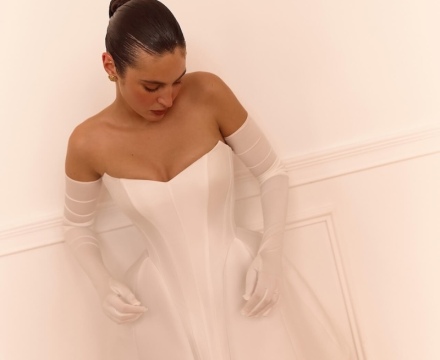 Abito da sposa corto in stile moderno con corpetto strutturato, scollatura omerale e guanti lunghi, presso Il Giardino Fiorito delle Spose a Roma.