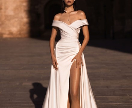 Abito da sposa con spalle scoperte e corpetto drappeggiato con spacco e silhouette fluida, creazione couture atelier Il Giardino Fiorito delle Spose Roma