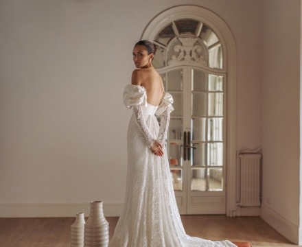 Abito da sposa in pizzo con spalle scoperte e maniche lunghe con spacco e silhouette aderente, creazione couture atelier Il Giardino Fiorito delle Spose Roma